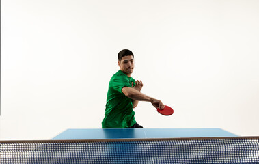 Dynamic portrait of athletic Asian man, professional ping-pong player training techniques in motion against white studio background. Concept of sport, hobby, lifestyle, match, victory, championship.