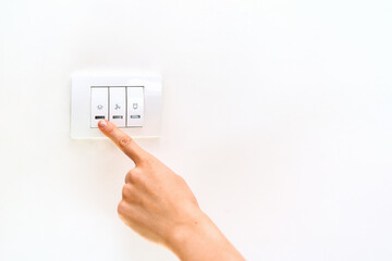 Female finger touches a light switch close-up. Saving energy at home.