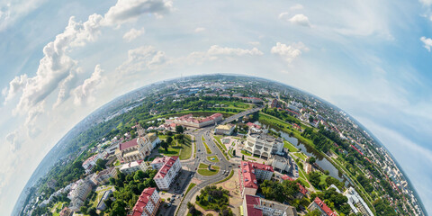 Aerial view from high altitude tiny planet in sky with clouds overlooking old town, urban development, buildings and crossroads. Transformation of spherical 360 panorama in abstract aerial view. - obrazy, fototapety, plakaty