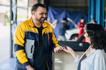 Customer women happy giving car key to mechanic worker for car service fix problem auto center...