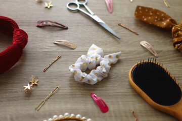 Wooden hairbrush, scissors and various headbands, hair clips and scrunchies on wooden background....