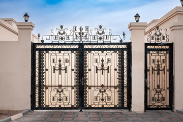 Double wrought-iron gate. Wrought iron gate and stone pillar. Black wrought iron entrance gates to rural property. © Elena_Alex
