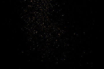 group of small golden flakes are scattered on the black surface - obrazy, fototapety, plakaty