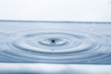 Captivating water droplet reflecting on a white background, forming an intriguing splash shape....