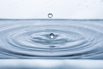 Dynamic water droplet splashing against a pristine white backdrop, forming intriguing shapes in...