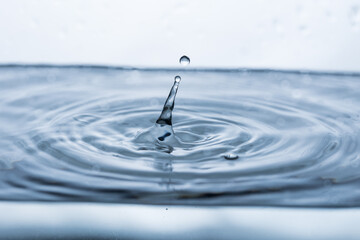 Captivating water droplet reflecting on a white surface, resembling a human figure. Ideal for...
