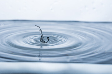 Dynamic water droplet reflecting on a clean white surface, creating a captivating splash. Ideal for...