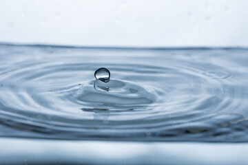 Vivid splash created by a water droplet reflecting off a pristine white surface. Perfect for illustrating purity and dynamic energy.