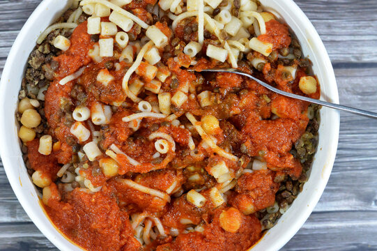Egyptian cuisine of Koshary, a popular street food made of rice, macaroni, spaghetti and lentils mixed together topped with a spiced tomato sauce, garlic vinegar, fried onions and hummus chickpeas