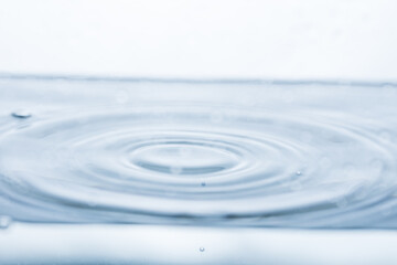 Dynamic water ripples captured in mid-motion against a pristine white backdrop. Ideal for illustrating fluid dynamics or the beauty of water droplets.