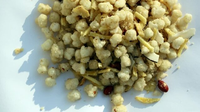 Sweet and Spicy deep fried Sago Sabudana Chivda or Chiwada table top spin spin isolated on white background.
