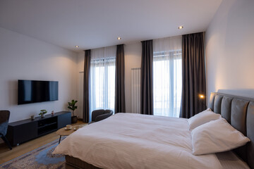 Interior of a bedroom with large master bed and wall mouted tv