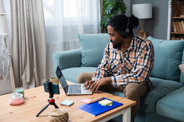 Young successful businessman sitting in home office preparing for video call presentation of product and marketing strategy. African American job seeker expects an online interview with an employer