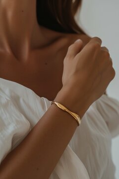 Thick gold bracelet on a woman's wrist. Quiet luxury concept. 