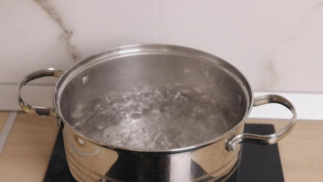 Tap water, Kitchen cookware, Water cookware. Water boils on electric stove in kitchen as part food preparation.