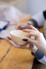 A teacher shows a student an uncoated cup in a clay modeling lesson