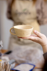 The teacher shows the students the finished work at the pottery master class