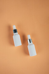 Cosmetic product in tube, bottle, lotion or serum seed on cream background. 