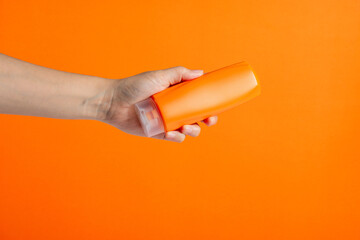 Shampoo bottle in hand isolated on orange background
