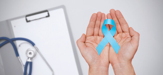 Hand holding blue prostate cancer awareness ribbon