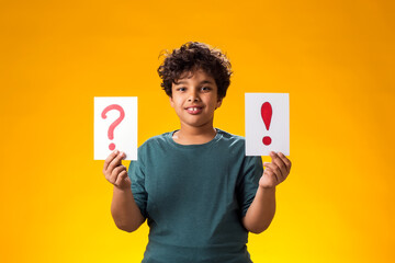 Kid boy holding question mark and exclamation point card in hand. Education and curiosity concept