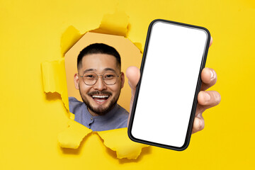 asian middle aged man presenting phone through ripped yellow paper