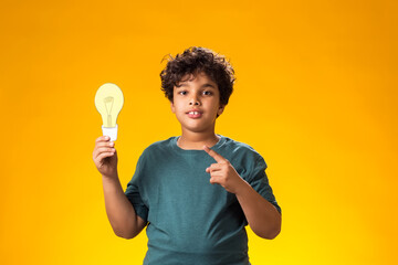Child boy holding paper bulb and pointing finger at it. Success, motivation, winner, genius, idea...