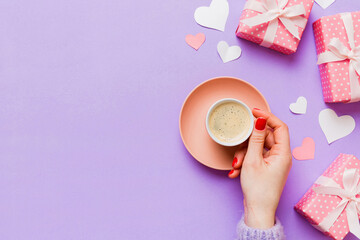 Flat lay of heart shaped cup of black coffee in the hands of women on colored background with copy...