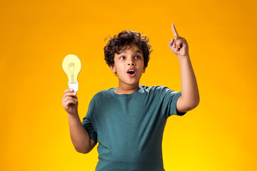 Surprised child boy holding paper bulb and holding finger up. Success, motivation, winner, genius, idea concept