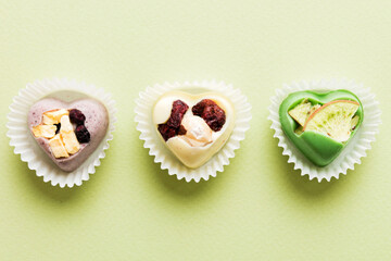 chocolate sweets in the form of a heart with fruits and nuts on a colored background. top view with space for text, holiday concept