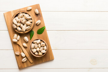 Fresh healthy Pistachios in bowl on colored table background. Top view Healthy eating concept....