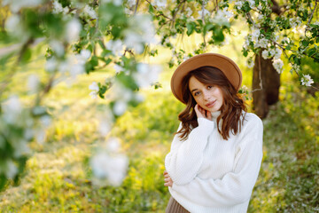 Young woman enjoying scent in blooming spring garden. The concept of youth, love, fashion, tourism and lifestyle