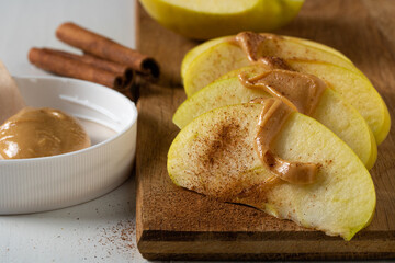 Sliced green apple with cinnamon and peanut butter