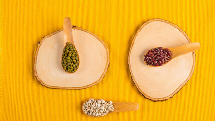 Mung beans and red kidney beans on spoon wooden on yellow background