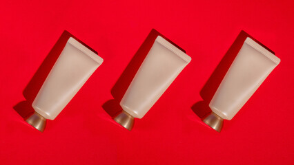 Plastic white tube for cream or lotion. Skin care or sunscreen cosmetic on red background.