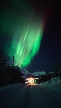 A snowy road beneath a beautiful aurora in Helgeland.