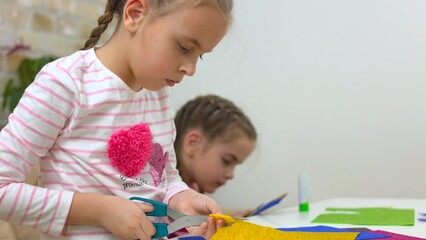 Two sisters cut out crafts from colored paper