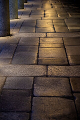 Arcade pavement made of stone slabs gleaming in artificial light, London
