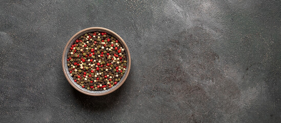 Various peppercorns in a bowl on a dark background. Mix of four peppers. Top view, banner. - obrazy, fototapety, plakaty
