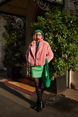 happy trendy woman in eyeglasses and faux fur jacket walking on night street in Vienna, Austria - 730076513
