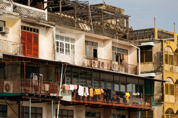 Fototapeta na wymiar The facade of aged riverside apartments in Bangkok, with laundry hanging to dry.