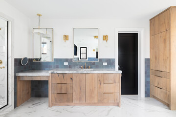 A luxurious bathroom with a wood vanity cabinet, blue tiles on the walls, gold accented lights and...