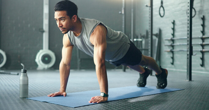 Fitness, man and pushups for muscle, exercise or training workout for strength or power at the gym. Athletic male in sport exercising lifting body with arms on the floor for strong muscles indoors