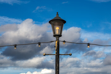 A decorative street lamp and string lights on Skegness seafront, with a blue sky behind
