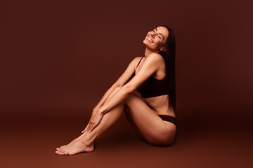 Fototapeta premium Full size photo no filter of attractive young woman sit floor enjoy procedure dressed stylish underwear isolated on brown color background