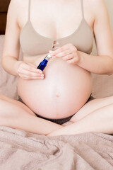 pregnant woman applying stretch mark cream to belly. pregnancy, people and maternity concept. pregnant apply anti-stretch mark cream on her belly