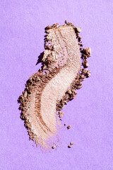 Eye shadow crushed powder golden beige smudged isolated on purple