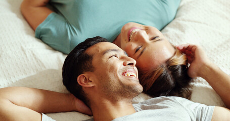 Happy couple, bedroom and talking while lying on bed for love and marriage bonding happiness in...