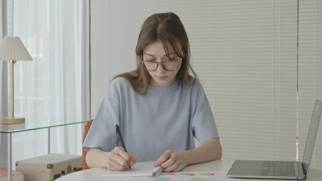 Female student with glasses writing in notebook