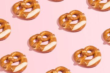 Fresh pretzels, traditional Bavarian pastry, creative pattern on pastel pink background, beer festival, snack.